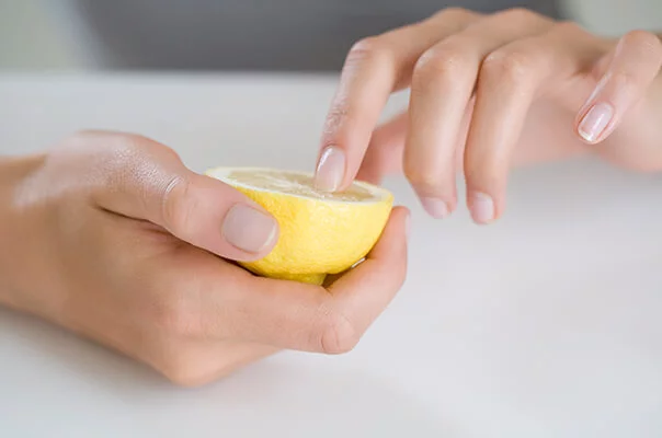 Frau, die ihre Fingernägel mit einer Zitrone aufhellt